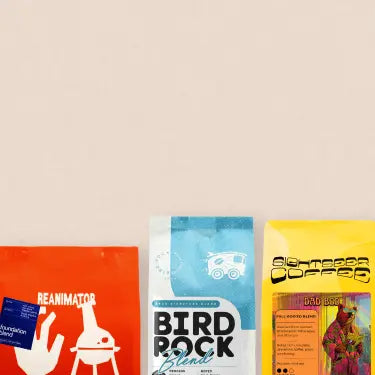 Collection of colorful coffee bags against on a beige background.