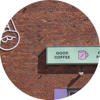 Brick wall with a sign advertising 'Good Coffee' and a logo.