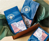  3 coffee bags from PT's Coffee Roasting Co in a box with green tissue paper. 