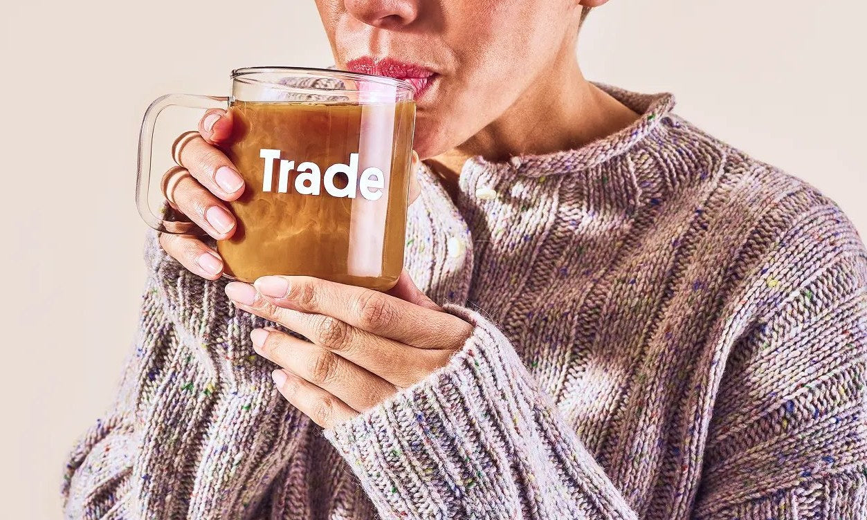 Someone sipping coffee from a Trade glass mug